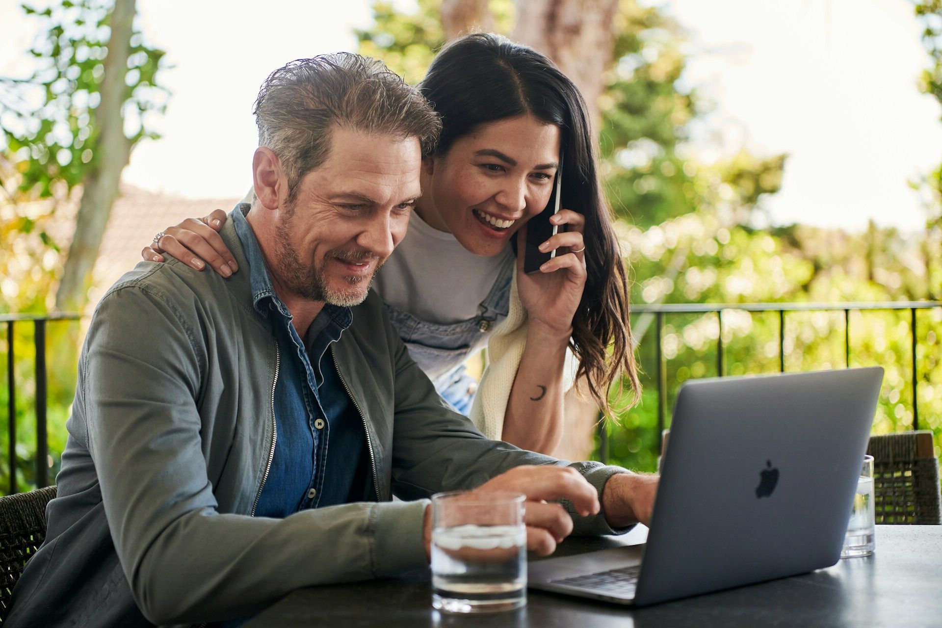 A couple reviewing a laptop together while speaking on the phone