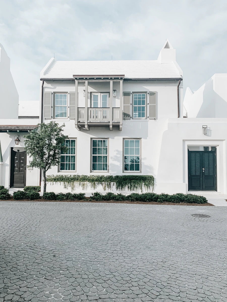 White coastal home with a balcony and green shutters